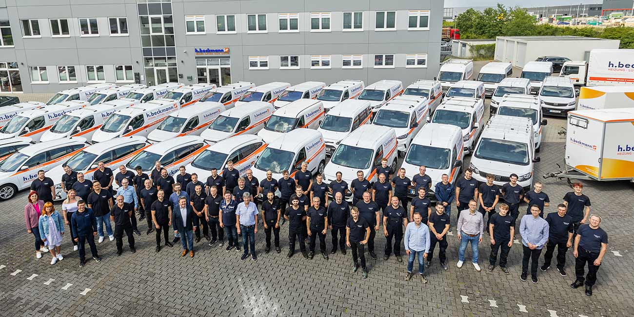 Beckmann-Team vor den Firmenfahrzeugen und dem Betriebsgebäude